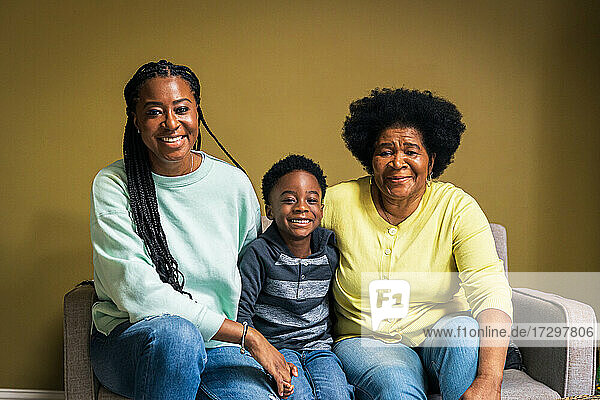 Porträt eines lächelnden Jungen mit Mutter und Großmutter zu Hause