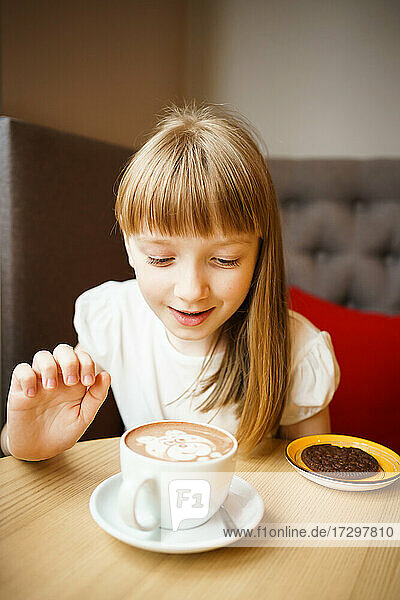 Niedliches kleines Mädchen sieht Kakao mit einem Muster an