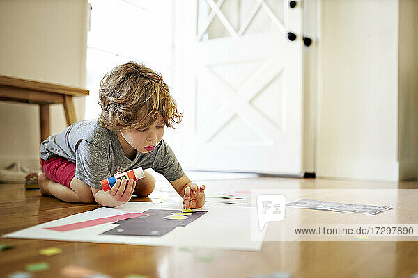 Boy holding glue while making paper art at home