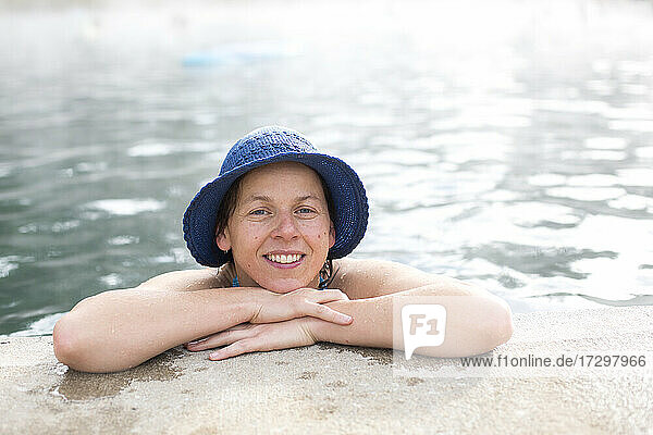 Porträt einer Frau mit blauem Hut  die sich am Rande eines Pools mit heißen Quellen ausruht