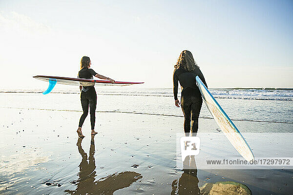 Zwei Freundinnen gehen zum Sonnenaufgang zum Surfen