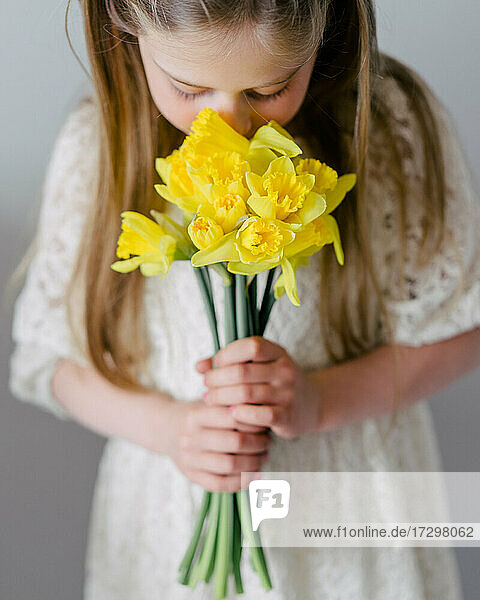 Ein junges Mädchen schnuppert an den schönen gelben Blüten der Narzisse. Frühling