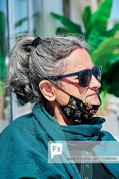 Porträt einer Frau mittleren Alters mit weißem Haar  Sonnenbrille und einer Maske unter dem Mund