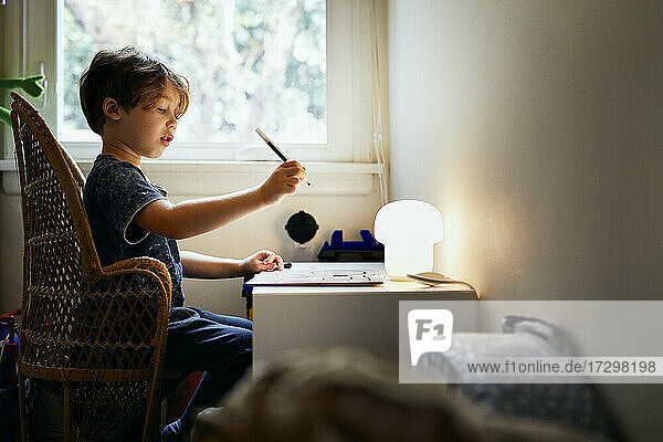 Boy drawing while sitting on chair at home