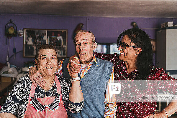 Portrait of a middle-aged daughter and her elderly parents hugging and smiling.