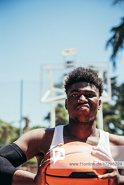 Porträt eines wütenden schwarzen Afro-Jungen mit trotzigem Blick  der den Basketball mit seinen Händen zusammendrückt. Bereit  ein Spiel zu spielen.
