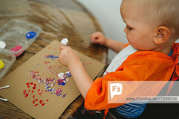 Seitenansicht eines Kleinkindes beim Malen und Experimentieren mit Farben zu Hause