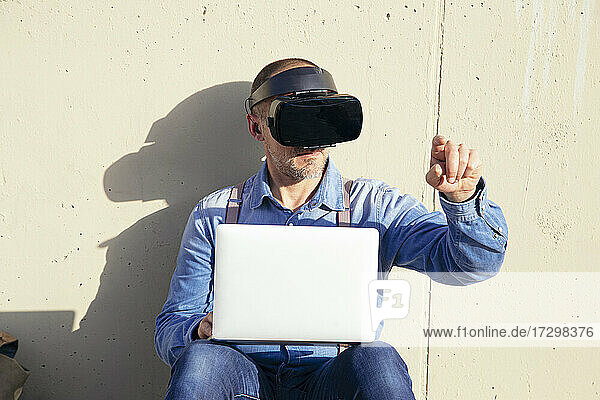 Geschäftsmann  der einen Virtual-Reality-Simulator untersucht  während er einen Laptop benutzt