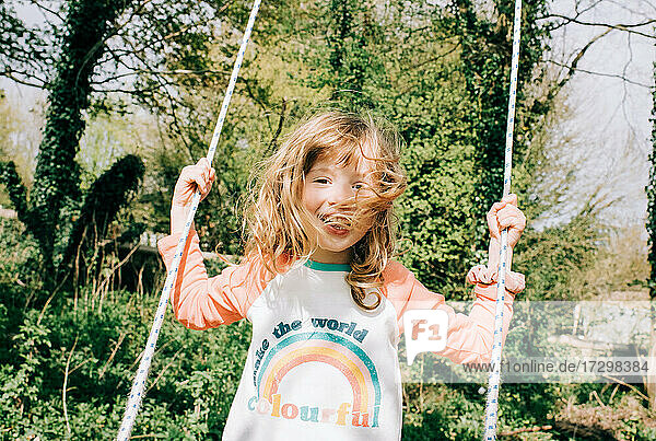 junges Mädchen schwimmt glücklich auf einer Schaukel in einem schönen Park in England