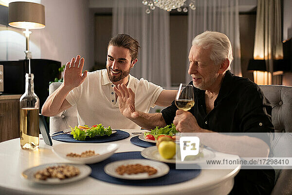 Junge und ältere Männer beim Videoanruf während des Abendessens