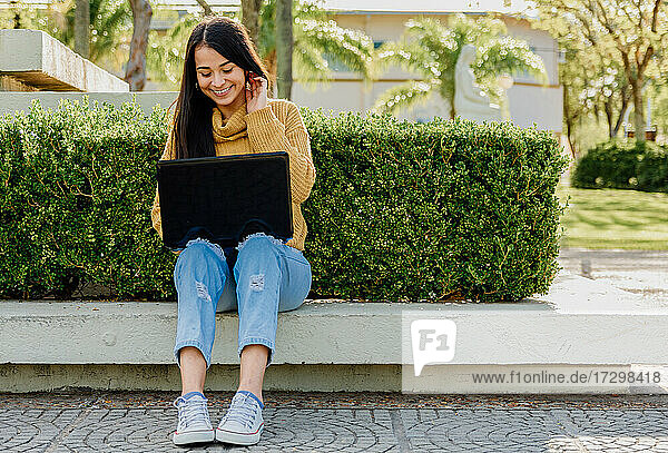 Junge Studentin mit Laptop lächelnd im Park
