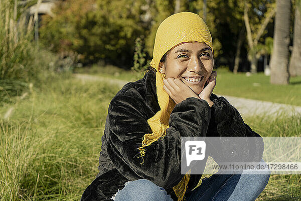 Junge Frau mit Brustkrebs  die sich einer Behandlung unterzieht. Sie lächelt  weil der Tumor verschwunden ist und es gute Nachrichten gibt. Sie trägt ein gelbes Halstuch oder einen Schal  um die Auswirkungen der Chemotherapie zu verbergen. Konzept Opti