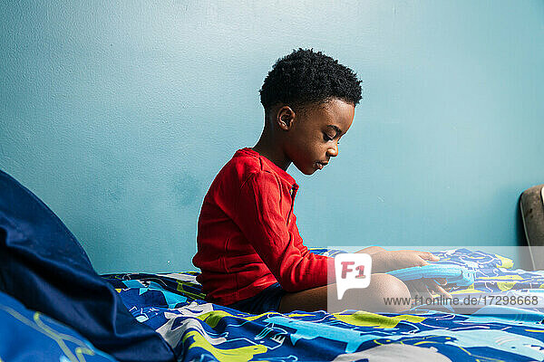 Boy using digital tablet on his bed