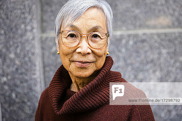 Porträt einer lässigen älteren Frau mit Blick in die Kamera in städtischer Umgebung