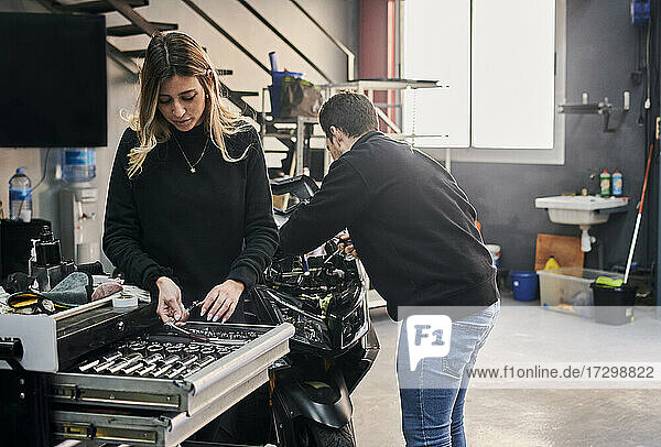 A woman and a man are working together in a mechanic shop
