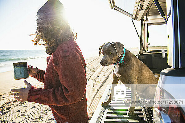 Frau und Hund am Morgen am Strand Auto-Camping