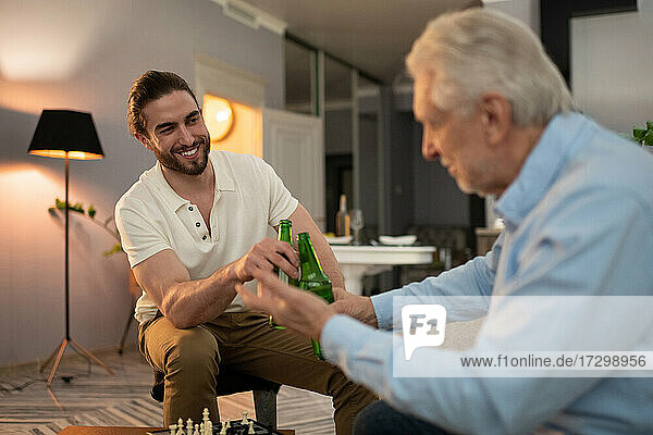 Grandson and grandfather proposing toast after chess game