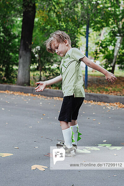 5 Jahre alt Junge Kind spielt im Freien  Kinder Outdoor-Aktivitäten  trägt grünes T-Shirt mit Dinosaurier-Druck und Dino-Helm
