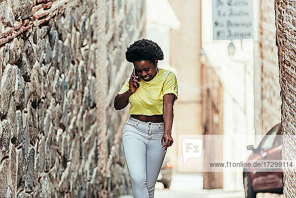 Porträt eines afroamerikanischen schwarzen Mädchens  das mit ihrem Handy telefoniert und auf einer Straße in der Altstadt tanzt.