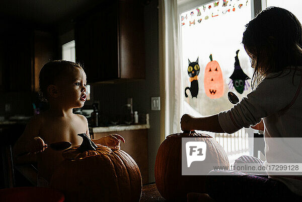 zwei Kinder beim Kürbisschnitzen zu Halloween in ihrem Haus