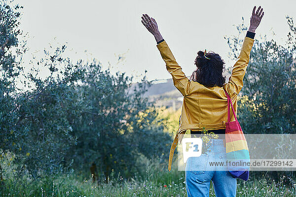 Woman raising her arms. She is in the field.