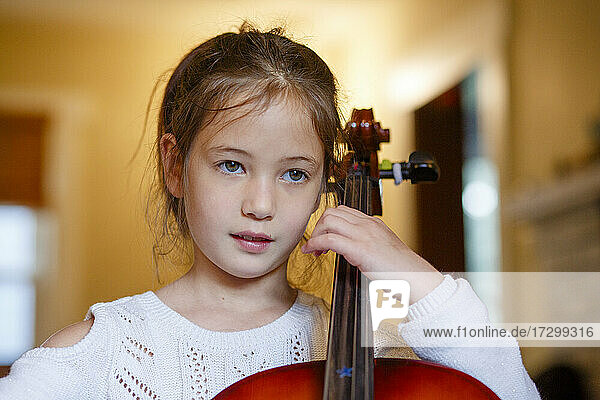 Nahaufnahme eines süßen Mädchens  das zu Hause Cello übt