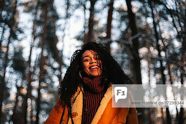 Porträt einer glücklichen jungen Frau  die im Winter im Wald steht