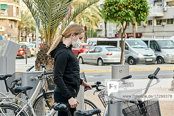 Eine junge Frau benutzt ein gemietetes Fahrrad  bevor sie Sport treibt