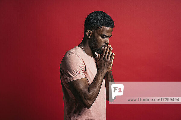 Porträt eines emotionalen schwarzen Mannes im Atelier mit betenden Händen