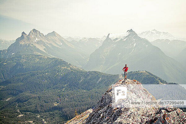 Ein Trailrunner steht auf dem luftigen Gipfel eines felsigen Bergrückens.