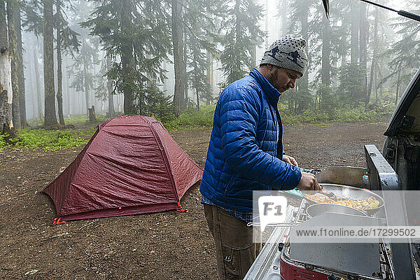 Frühstück kochen beim Camping im nebligen Wald