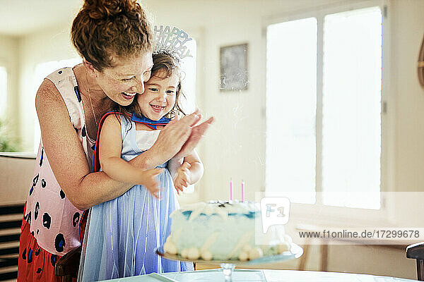 Glückliche Mutter klatscht  während sie den Geburtstag ihrer Tochter zu Hause feiert