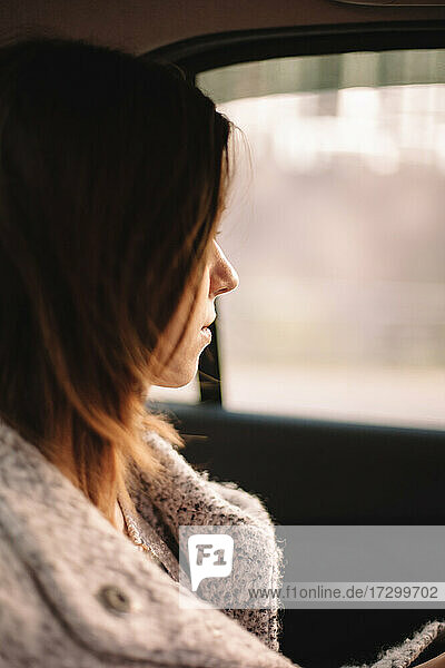 Nachdenkliche junge Frau  die durch das Fenster schaut  während sie im Auto fährt