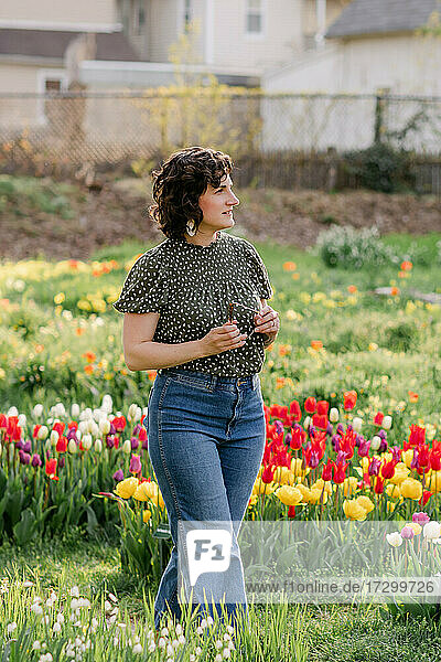 Woman walking amongst tulips in urban garden