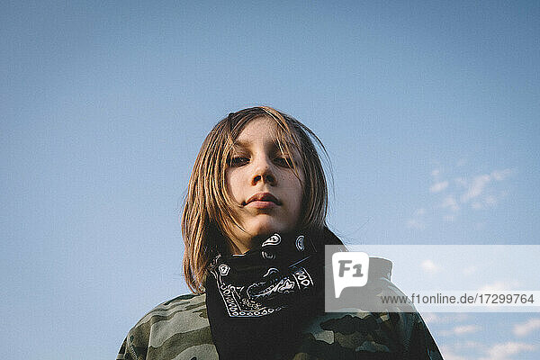 Junge in Camouflage Hoodie und Bandana gegen den offenen blauen Himmel
