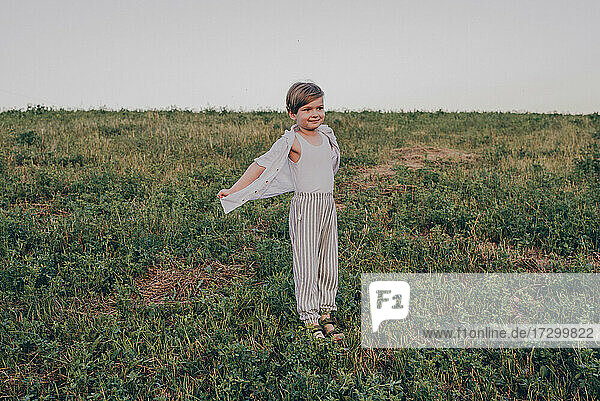 Porträt eines glücklichen 5 Jahre kleinen niedlichen Jungen  mit weißem Hemd im Feld auf grünem Gras stehend