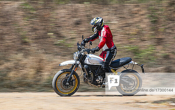 man riding his scrambler type motorcycle on dirt track in Thailand