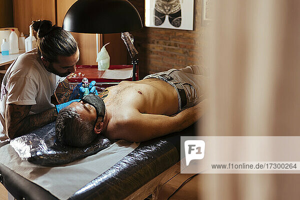 Tattoo artist working on a customer's arm in his studio.