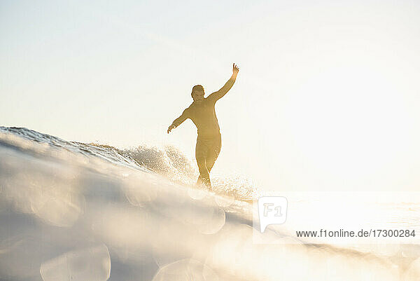 Gegenlicht Mann Surfen auf einer Welle im Sommer Sonnenuntergang