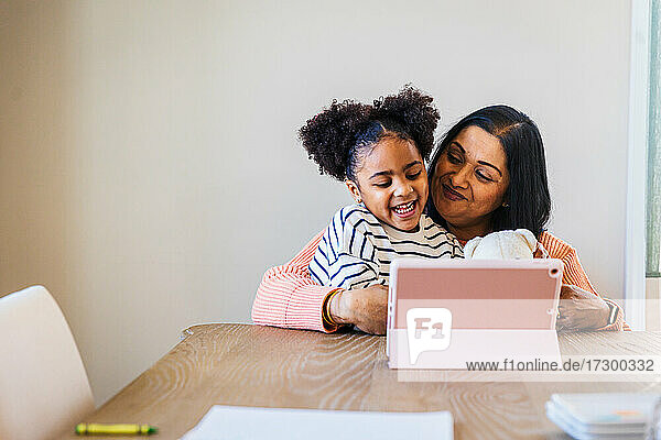 Lächelnde Enkelin und Großmutter verwenden digitales Tablet zu Hause