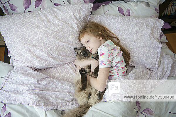 Krankes kleines Mädchen kuschelt mit Katze im Bett