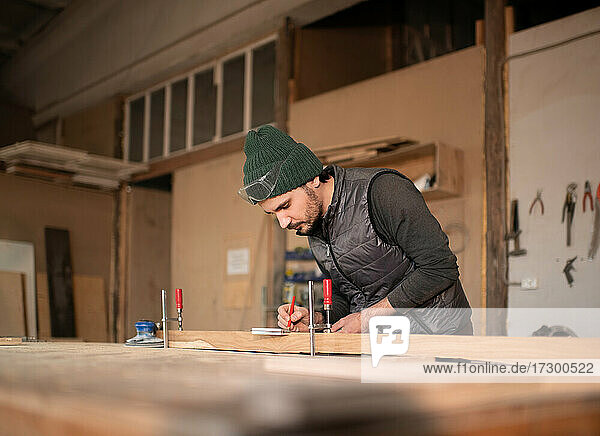 Männlicher Zimmermann macht Markierungen auf einer Planke