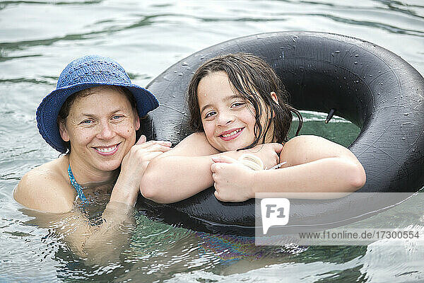 Porträt einer Mutter und ihrer elfjährigen Tochter  die im Pool schwimmen
