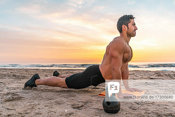 muscular man training on the beach at sunrise