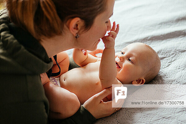 Bezauberndes nacktes Baby untersucht das Gesicht der Mutter