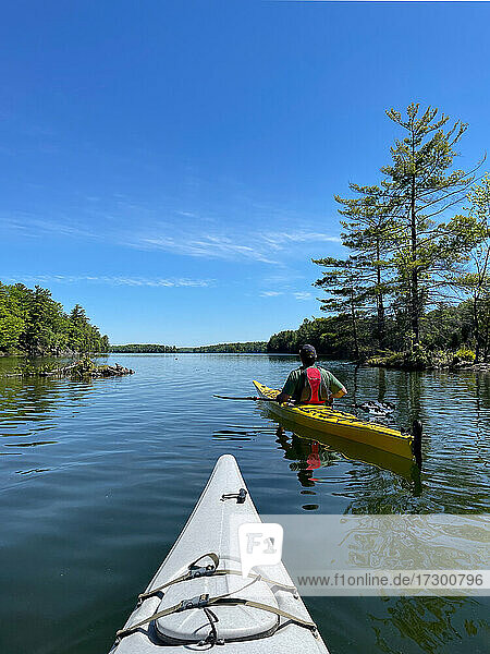 Two kayaks being paddled on lake in Ontario  Canada on sunny day.
