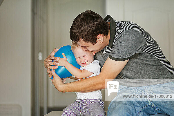 Vater und Sohn lachen und umarmen sich mit blauem Luftballon