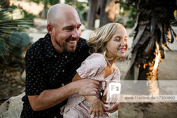 Vater kitzelt Tochter im Garten in San Diego