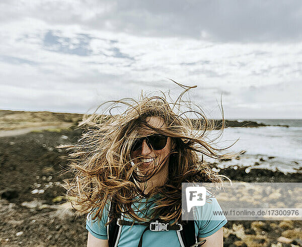 Frau mit vom Wind zerzaustem Haar lächelt beim Wandern auf Hawaii