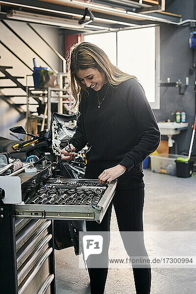 Eine glückliche Frau arbeitet in einer Autowerkstatt